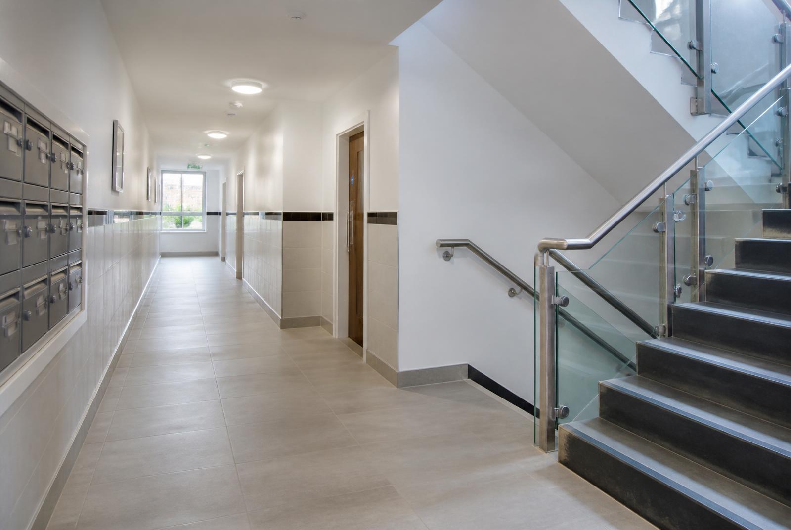 Freshly cleaned communal hallway of a UK apartment block with polished tiled floor, wiped mailboxes and dust-free stairwell