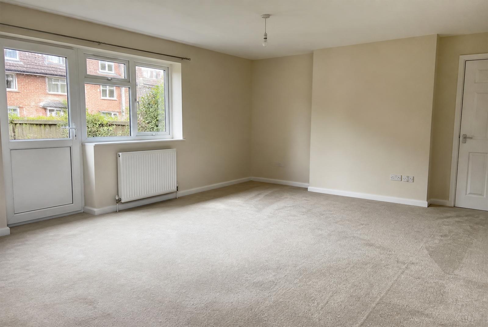 Empty freshly cleaned UK rental living room after a deposit-standard end-of-tenancy clean with vacuumed carpet and streak-free windows